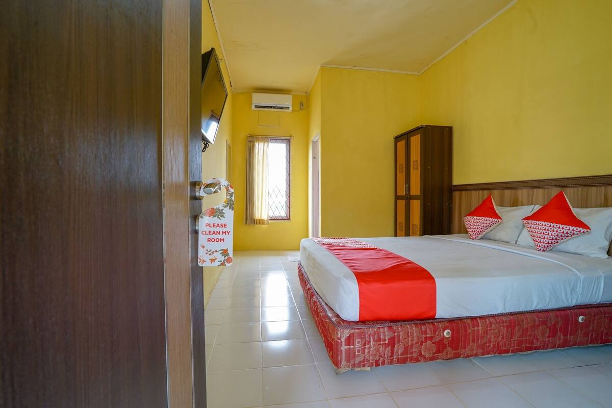 Une chambre d’hôtel avec un lit, une armoire, une fenêtre avec des rideaux et une pancarte sur la porte.