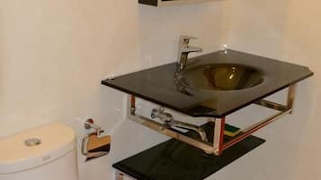Un baño con inodoro blanco, lavamanos negro y un espejo encima, además de un pequeño cubo de basura.