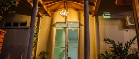 A building entrance with a wooden porch, a glass door, and potted plants.