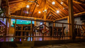 A spacious indoor area with a high wooden ceiling, multiple ceiling fans, and hanging light fixtures. - Charming Holiday Lodge (Hulhudhoo)