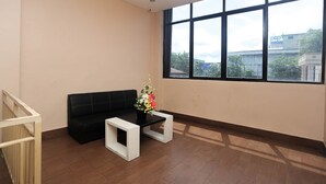 A room with a black sofa, a small white table, and a potted plant.