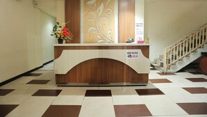 A reception desk with a wooden finish and a decorative panel. A sign indicates a helpline.