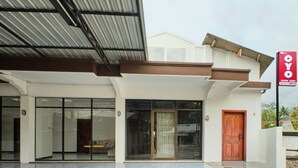 A modern building with a large glass entrance, a wooden door, and a signboard. - OYO 2519 Mayang Garini (Borobudur)