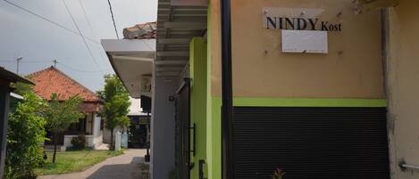 Un bâtiment sur lequel on peut lire l’inscription « NINDY Kost » et une pancarte qui fait de la publicité pour « Nindy Homestay ».