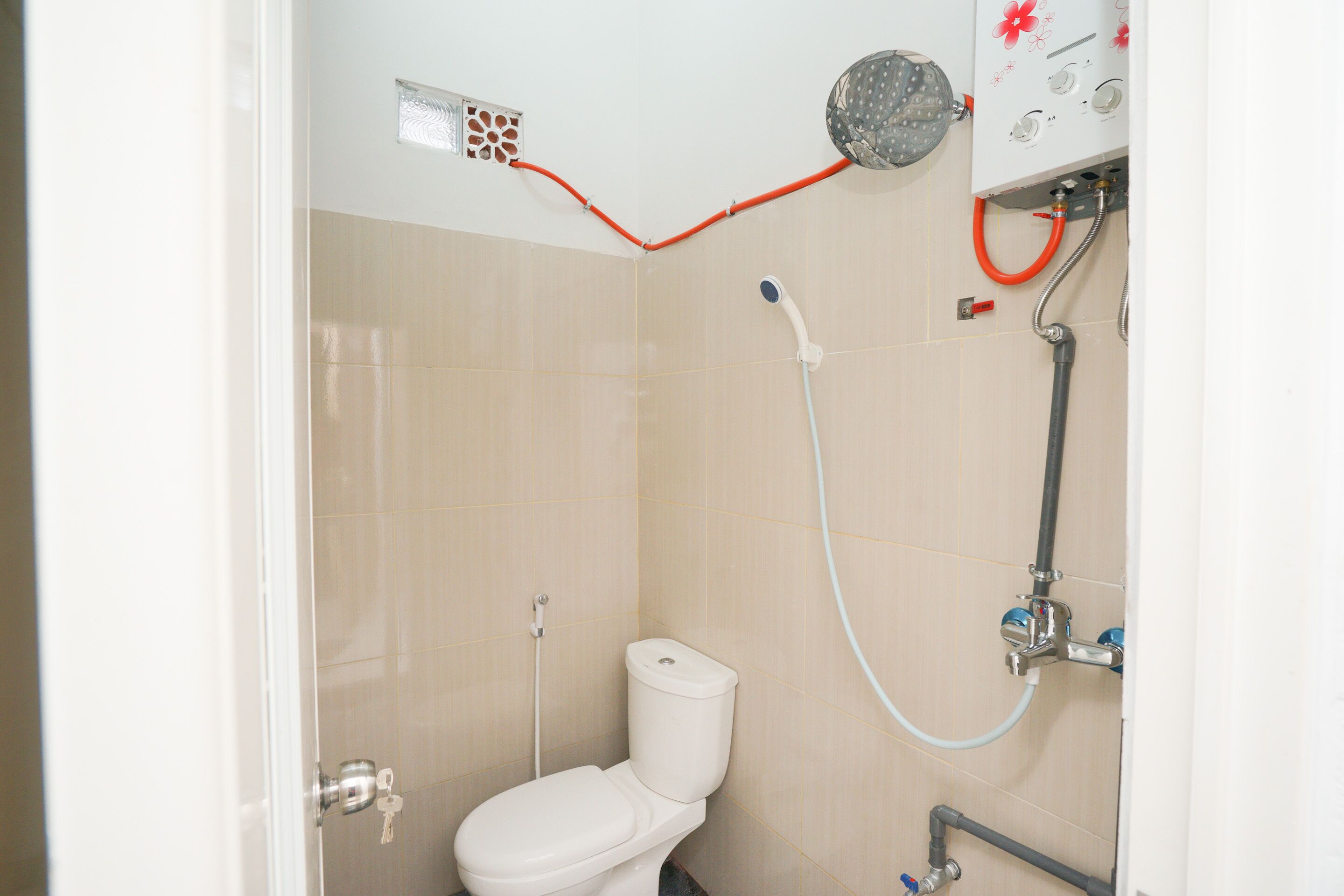 A bathroom with a toilet, shower, and visible plumbing.