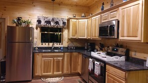 A wooden cabin-style kitchen with a stainless steel refrigerator, a microwave, and wooden cabinets. - Princesses Mountain View ,  Romantic/Honeymoon getaway   (Sevierville)