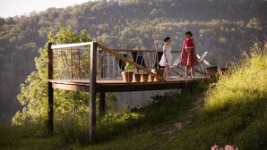 A wooden deck with a glass enclosure, overlooking a forested hillside. - Hotel Le Morimont (Oberlarg)