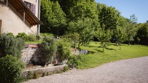 A building with a stone foundation and wooden beams, surrounded by lush greenery and trees. - Hotel Le Morimont (Oberlarg)