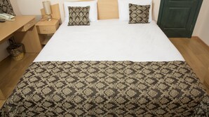 A hotel room with a bed, bedside table, lamp, and a green door.