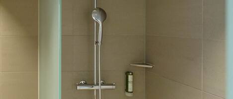 A modern shower with a handheld showerhead and a wall-mounted control panel.