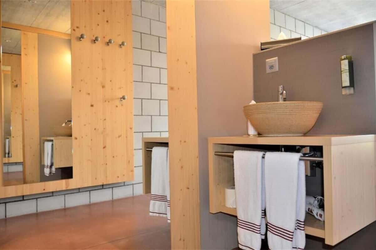 A modern bathroom with a wooden vanity, a large mirror, and a vessel sink.