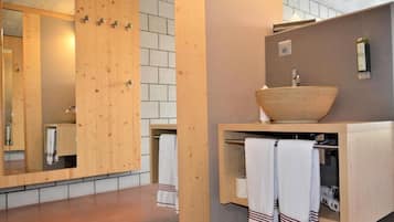Un baño moderno con tocador de madera, un espejo grande y un lavabo sobre encimera.