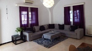 A modern living room with a grey sofa, a coffee table, and purple curtains.