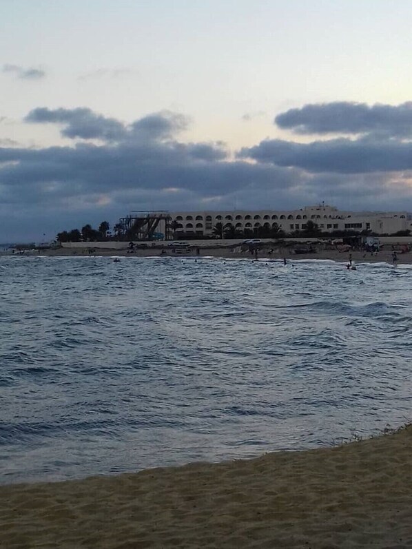 A coastal building with a series of arches and a sandy beach in the foreground.