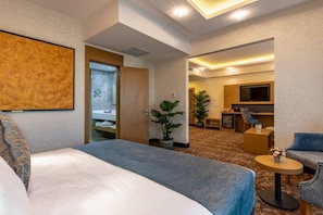 Habitación de hotel con cama, televisión, zona de estar y baño.
