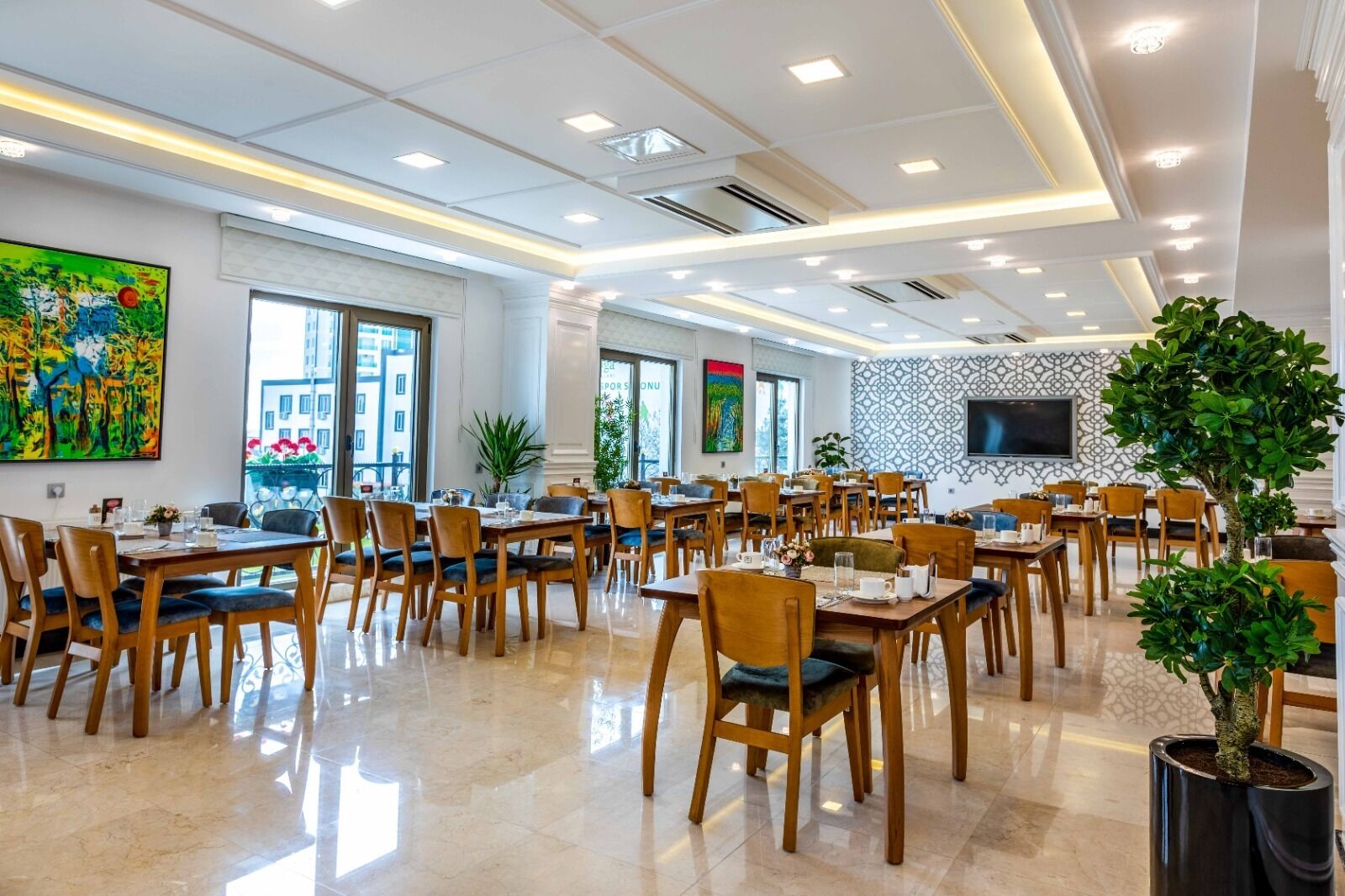 Un comedor amplio con varias mesas y sillas, ventanas grandes y un diseño de techo moderno.