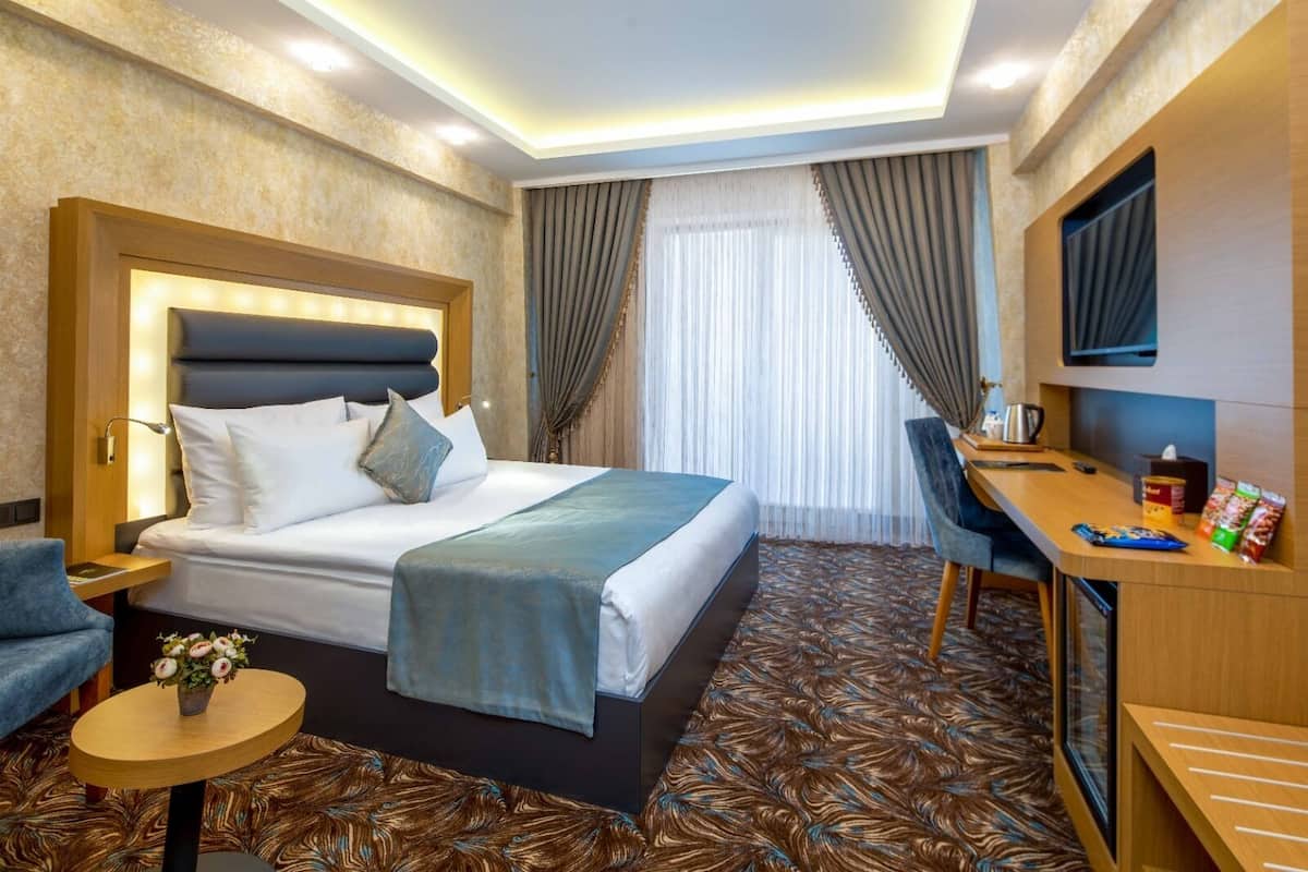 Una habitación de hotel con cama, mesita de noche, silla, escritorio y televisor.