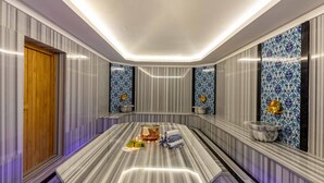 Un baño moderno con tocador de mármol, puerta de madera y azulejos decorativos.