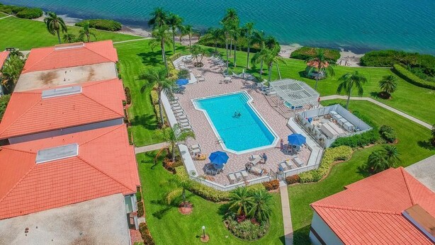 Vista aérea de un resort con piscina central, rodeado de palmeras y una zona de playa.