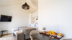 A modern hotel room with a bed, a dining table with breakfast, and a TV on the wall. - Escarpa - the Madeira Hideaway (Ponta do Sol)