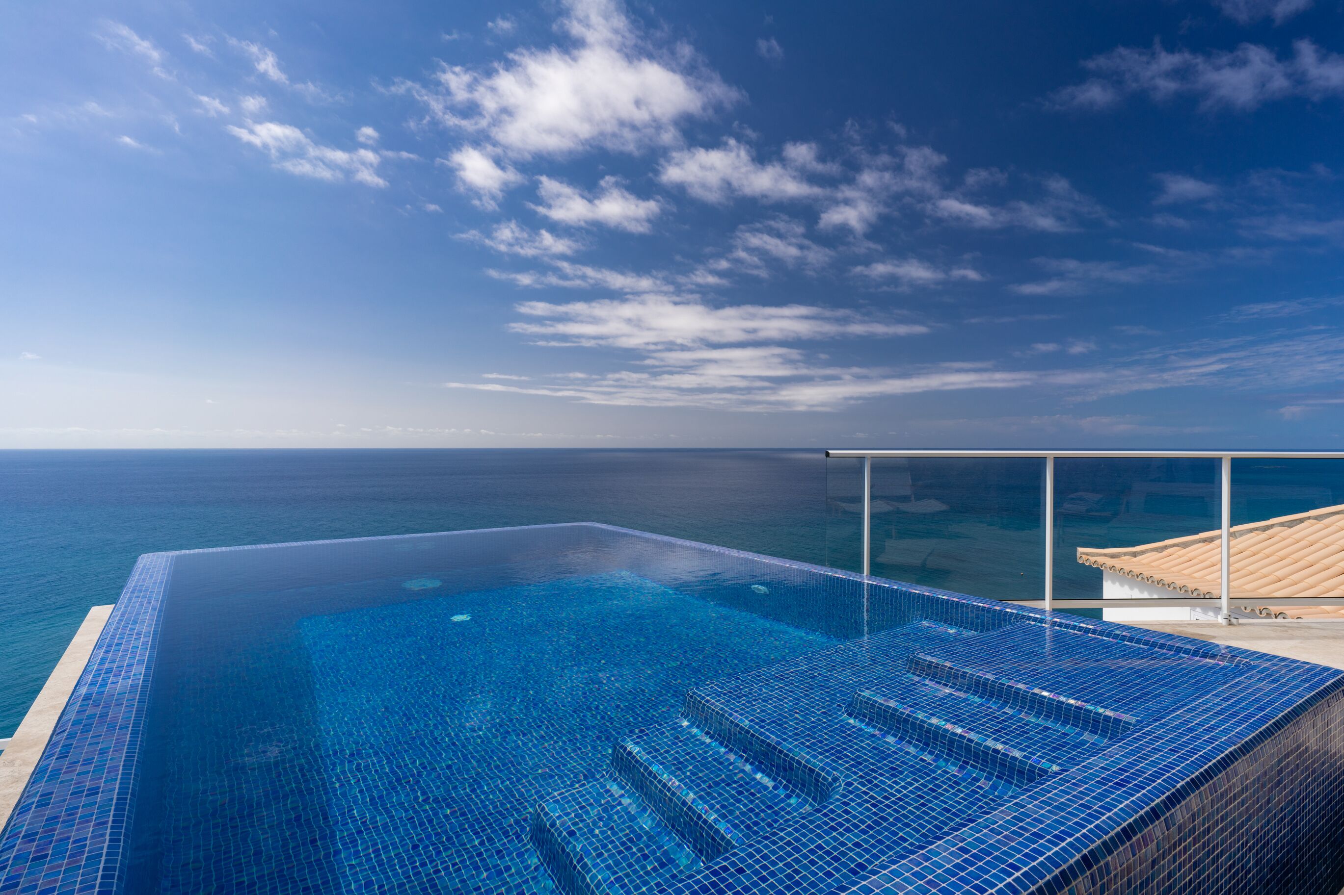 A infinity pool with a clear view of the ocean and sky.