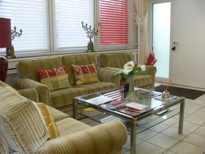 A living room with striped sofas, a glass coffee table, and a door with a coat rack. - Die Villa Mettmann (Mettmann)