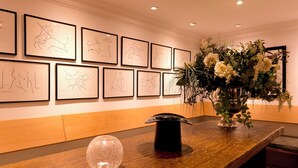 A reception area with framed artwork on the wall, a vase with flowers on the counter, and a decorative glass sphere. - Die Villa Mettmann (Mettmann)
