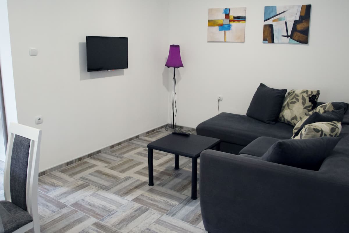 A modern living room with a grey sofa, a small black table, a floor lamp, and abstract wall art.