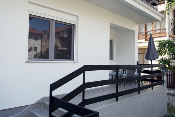 A modern building with a staircase, a balcony with a table and chairs, and a large window. - Apartments Velickovic (Soko Banja)