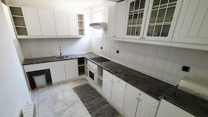 A kitchen with white cabinets, a black countertop, a sink, and a stove. - Apartments Velickovic (Soko Banja)