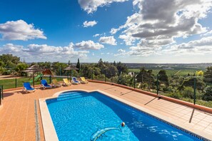 A swimming pool with blue water, surrounded by a tiled deck with lounge chairs. - Villa da Horta, a beautiful extensive villa in a peaceful location (Alcantarilha)