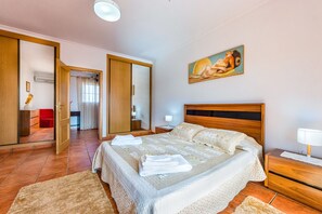 A bedroom with a large bed, a nightstand, a painting, and a mirror. - Villa da Horta, a beautiful extensive villa in a peaceful location (Alcantarilha)