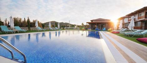 Alberca al aire libre, sombrillas en la alberca y camastros