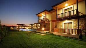 A two-story house with a swimming pool, stone facade, and a well-lit balcony. - Karaincir Suit Otel (Datça)