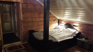 A wooden cabin bedroom with a bed, a nightstand, and a small table.