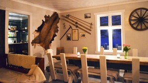 A dining area with a wooden table and chairs, a large wooden sculpture, and a wall-mounted wheel. - Rødseter Inn (Sogndal)