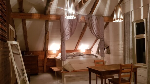 A cozy attic bedroom with a bed, wooden furniture, and a sloped ceiling. - Rødseter Inn (Sogndal)