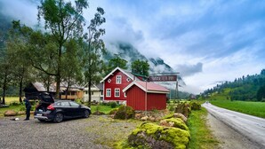 A red building with a sign reading "Rødseter Inn" in a rural setting with a gravel road and greenery. - Rødseter Inn (Sogndal)