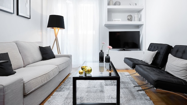 A modern living room with a grey sofa, a black sofa, a glass coffee table, and a black floor lamp. - Lux Central Apartment At Kolonaki (Athens)