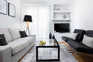 A modern living room with a grey sofa, a black sofa, a glass coffee table, and a black floor lamp.