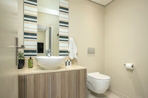 A modern bathroom with a large sink, a toilet, and a mirror with striped panels. - 801 The Tyrwhitt Rosebank - Adults Only (Johannesburg)