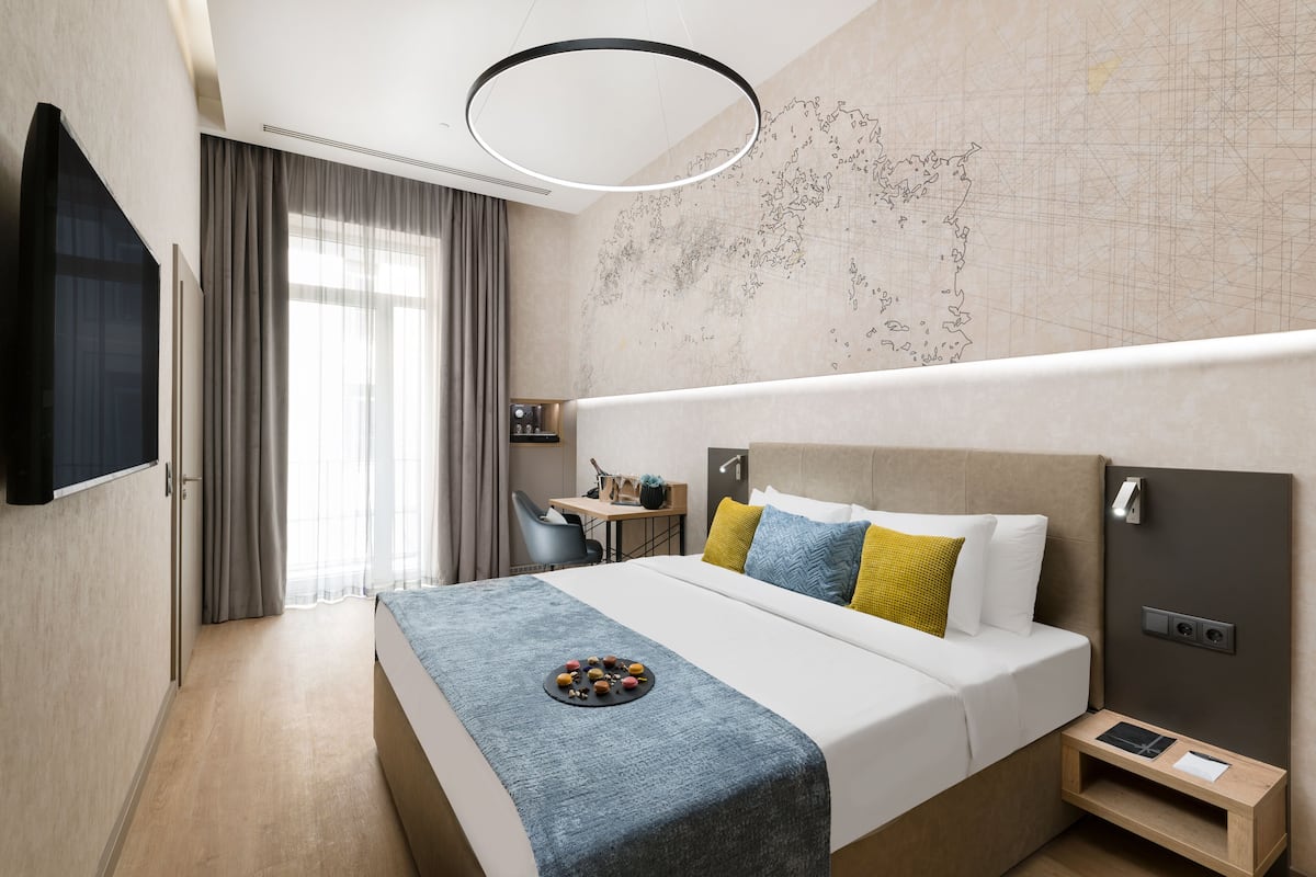 A modern hotel room with a large bed, a desk, and a map on the wall.