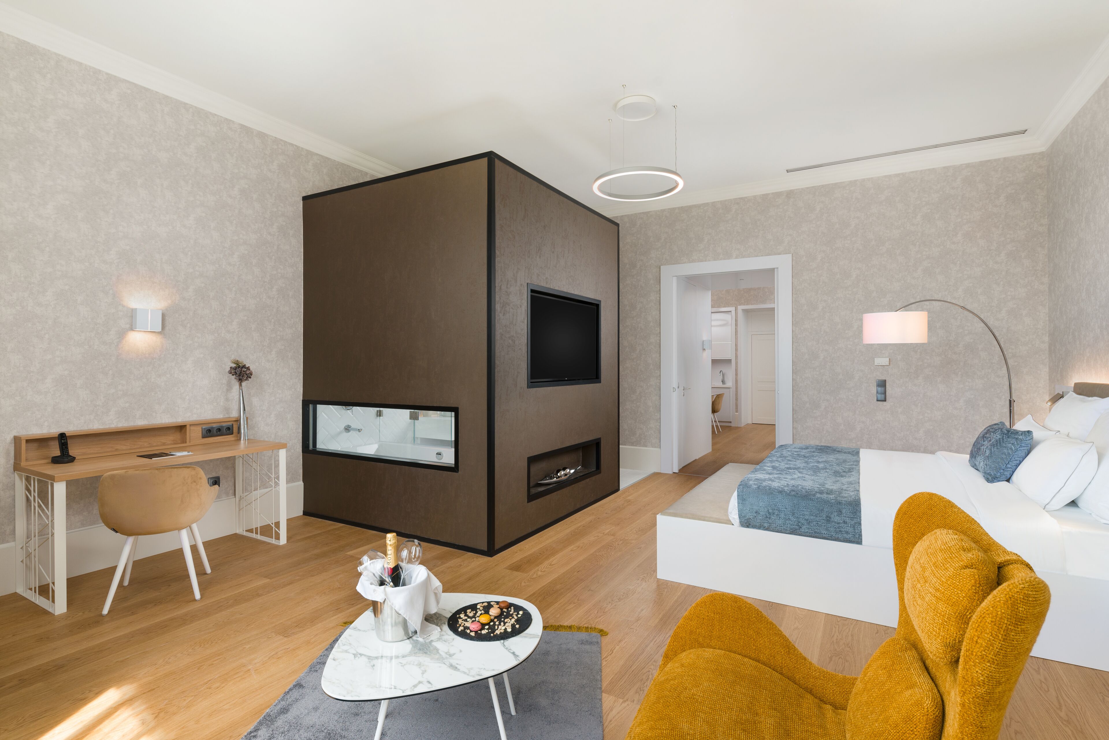 Et moderne hotelværelse med et træskrivebord, en sofa, et fjernsyn og en pejs.