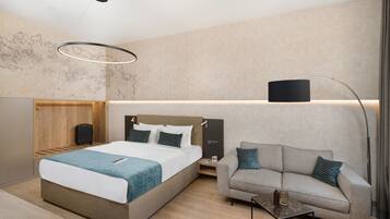 Una habitación de hotel moderna con una cama grande, un sofá, una mesita y una lámpara de pie.
