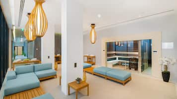 Un vestíbulo moderno con sofás azules, mesas de madera y lámparas colgantes.