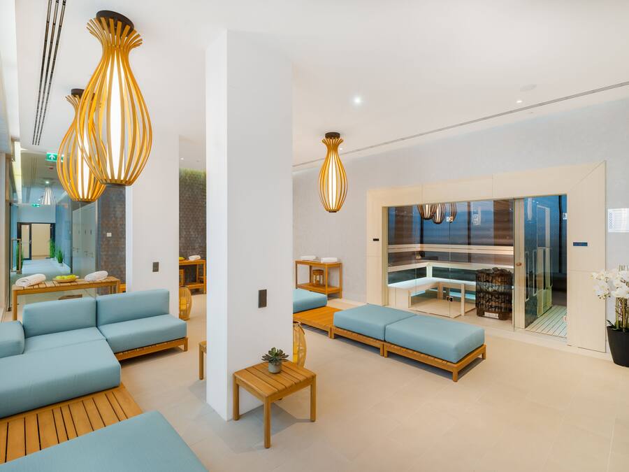 Un vestíbulo moderno con sofás azules, mesas de madera y lámparas colgantes.