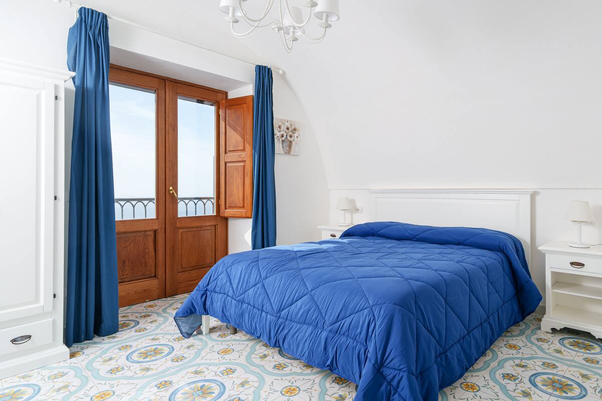 A bedroom with a large bed, a wooden door, and a patterned floor.