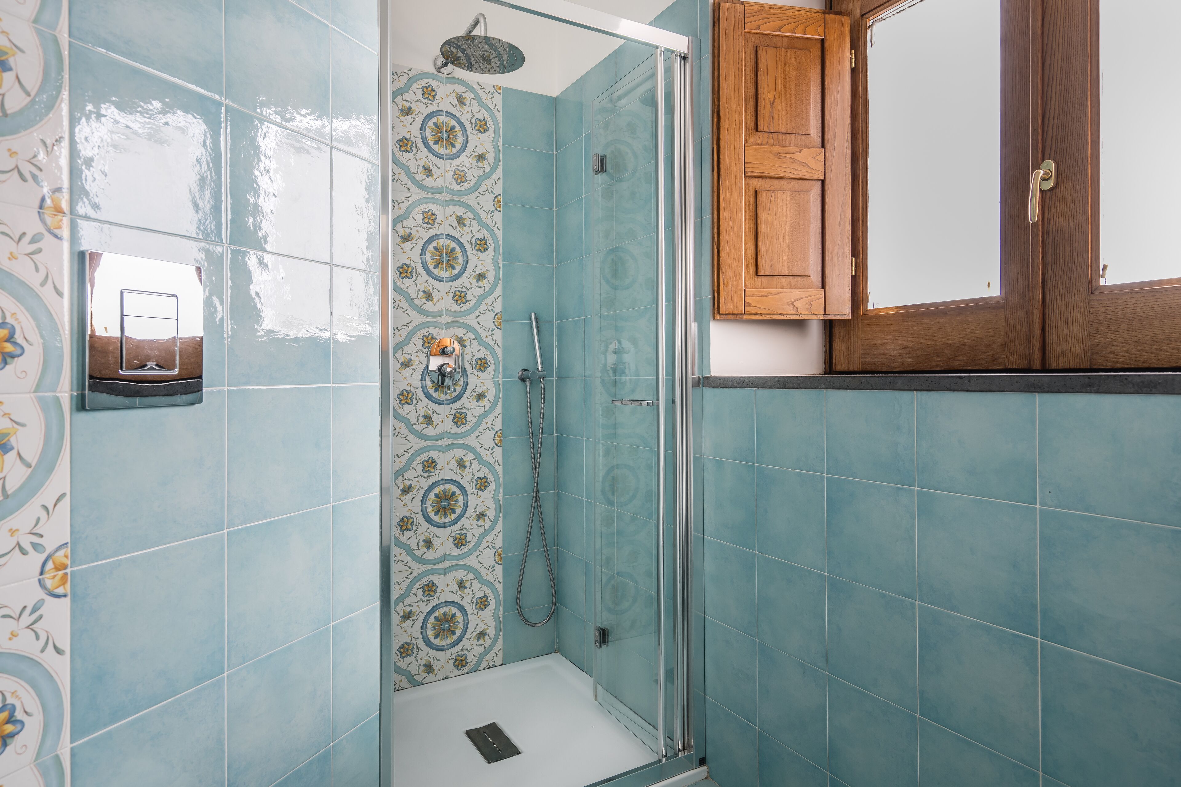 Un baño con azulejos azules, una ducha y una puerta de madera.