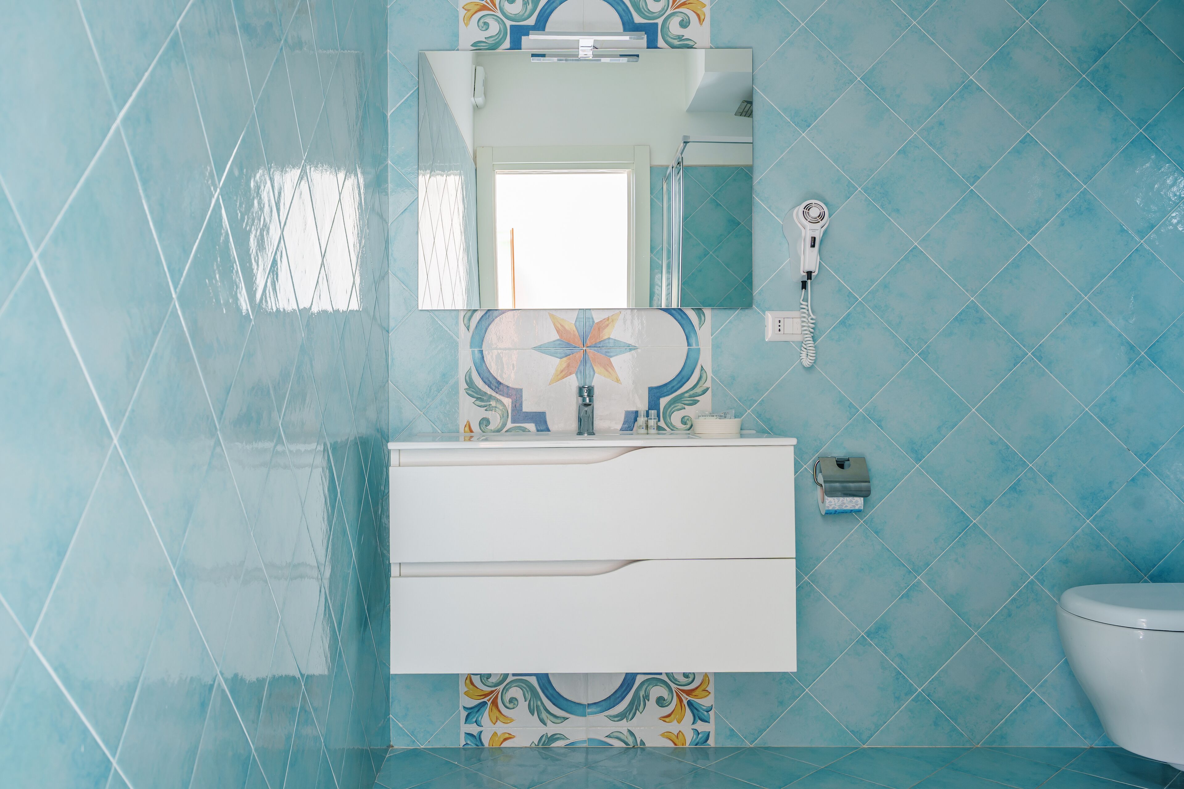 A bathroom with a white vanity, a mirror, and a toilet.