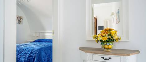 A bedroom with a bed, a dresser, a mirror, and a vase of flowers.